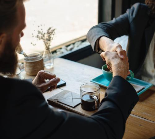 Adults shaking hands over beverage