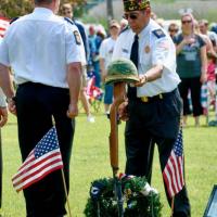 Veterans next to helmet on top of memorial