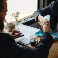 Adults shaking hands over beverage