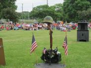 Helmet on rifle next to two flags in grass